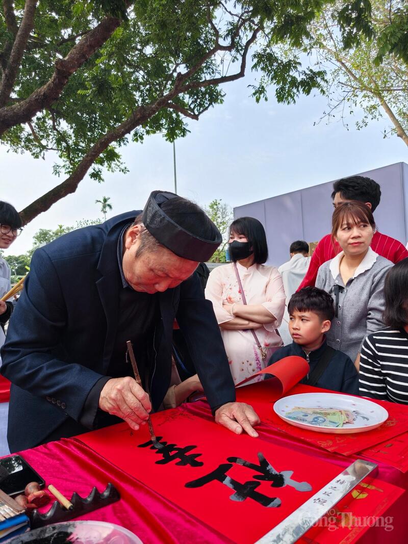 Ông đồ chăm chút từng nét bút trên nền giấy đỏ.