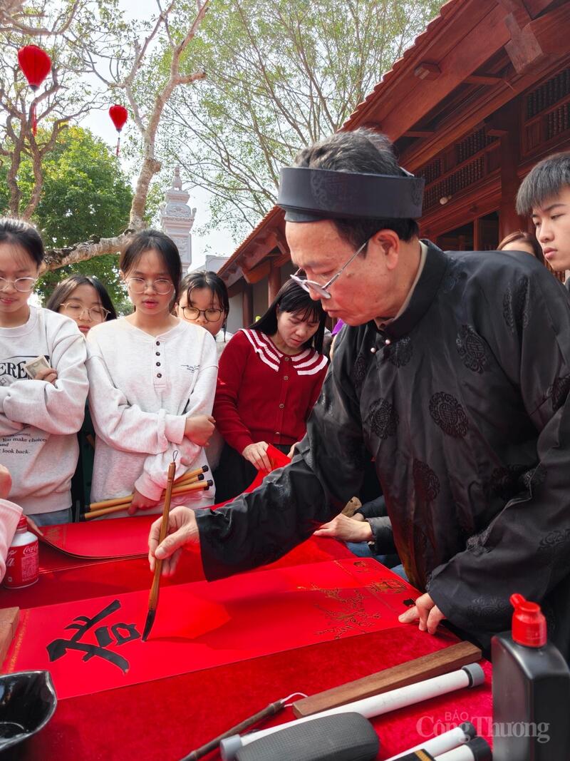 Các bạn trẻ chăm chú xem ông đồ trình diễn thư pháp.