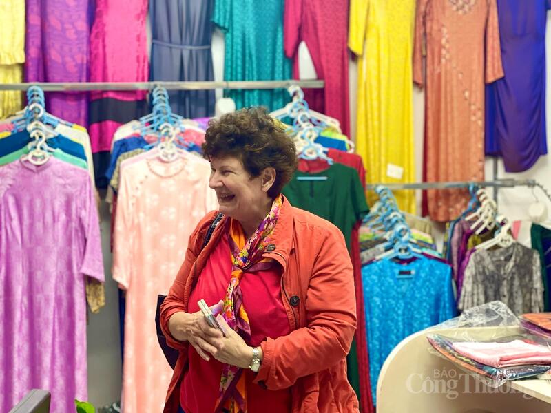 Du khách nước ngoài thích thú lựa chọn áo dài lụa làm đồ lưu niệm. Ảnh: Nhật Chi