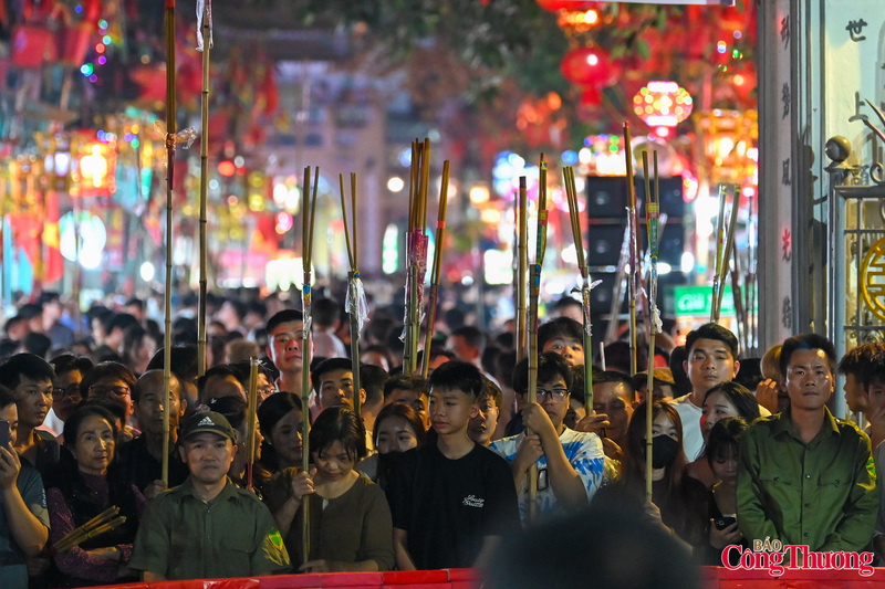 Trong không gian linh thiêng, người dân tay cầm hương, đèn hoặc bó đuốc nhỏ kiên nhẫn chờ đến lượt nhận lửa.