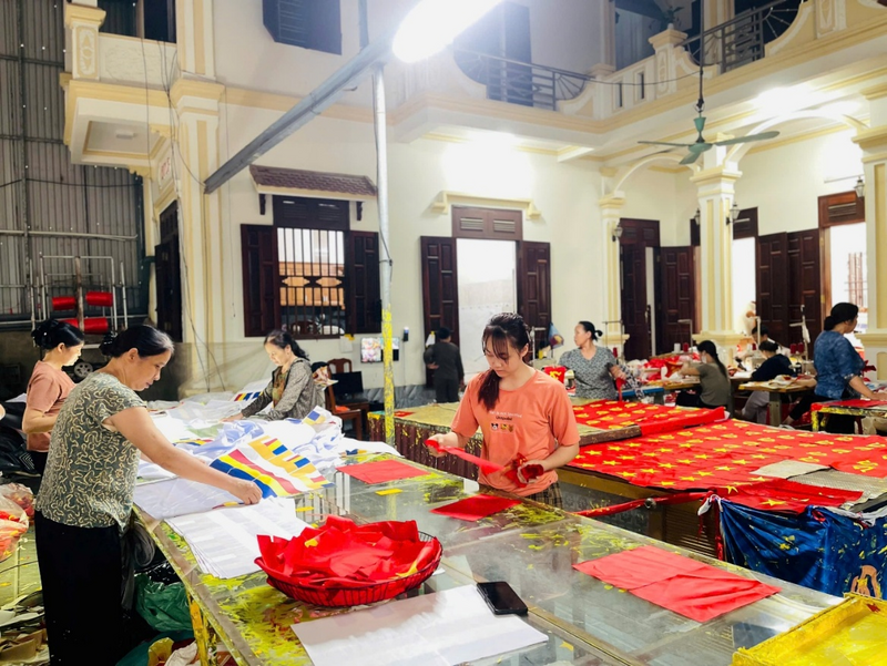 Có mặt tại xưởng sản xuất lớn nhất làng Từ Vân, hàng chục công nhân đã miệt mài làm việc từ sáng sớm. Trước đây, cờ chủ yếu được làm thủ công bằng tay, tốn rất nhiều thời gian và cần nhiều người làm. Song, hiện nay cơ sở đã chuẩn bị máy móc sản xuất hiện đại, tự động nên độ chính xác cao, giúp tăng năng suất so với phương thức truyền thống. Ảnh: Mai Linh