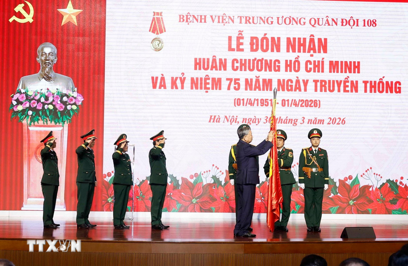 Tổng Bí thư Tô Lâm, Bí thư Quân ủy Trung ương gắn Huân chương Hồ Chí Minh lên Quân kỳ Quyết thắng của Bệnh viện Trung ương Quân đội 108. Ảnh: Thống Nhất/TTXVN
