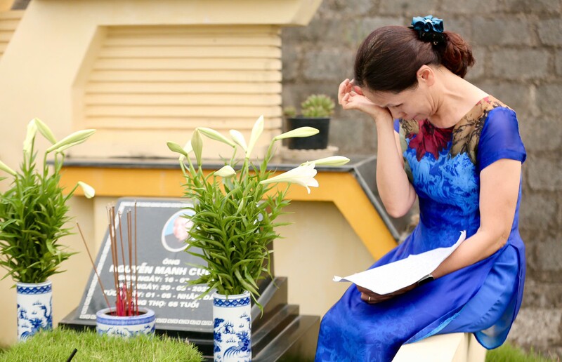 Mỗi lần đến mộ, bà Mai thắp một nén hương, bật lại những bản nhạc mà chồng từng yêu thích, rồi đọc những dòng nhật ký. Trong không gian tĩnh lặng, giọng đọc của bà đôi lúc nghẹn lại, nước mắt lặng lẽ rơi. Nhưng chính những khoảnh khắc ấy lại trở thành sợi dây kết nối vô hình giữa hai thế giới. Ảnh: Ngô Nhung