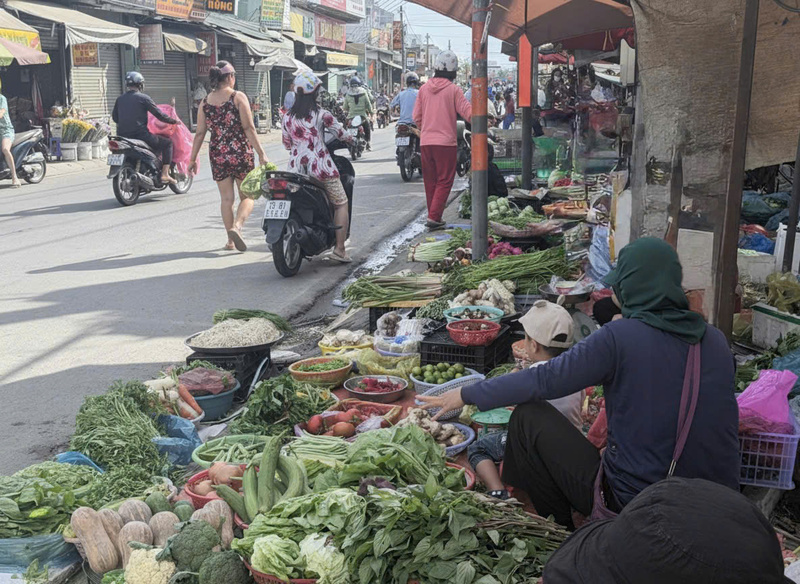 Rau củ, trái cây là mặt hàng dễ bị ảnh hưởng bởi nắng nóng, tiểu thương phải liên tục tưới nước để giữ độ tươi khi bày bán ngoài trời. Ảnh: Minh Anh.