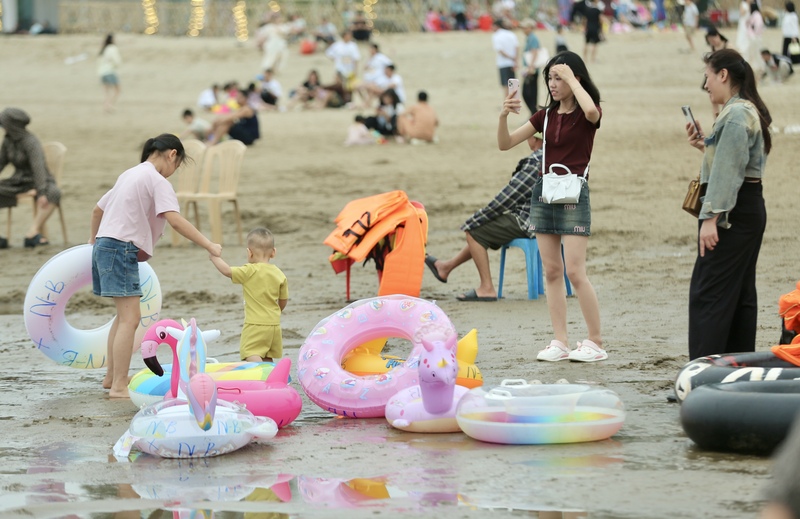 Các gian hàng bán đồ lưu niệm, diều nhiều màu sắc, đồ chơi trẻ em thu hút đông đảo người mua, nhất là các gia đình có trẻ nhỏ. Bên cạnh đó, dịch vụ cho thuê phao bơi, áo phao, ghế nằm luôn trong tình trạng kín khách, nhiều thời điểm phải chờ đến lượt. Ảnh: Ngô Nhung