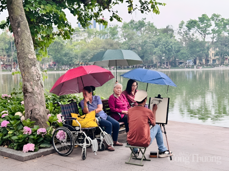 Tiếp nối những khoảnh khắc ấy, người họa sĩ vẫn lặng lẽ hoàn thiện từng nét vẽ trong không gian tĩnh lặng, nơi thời gian như chậm lại dưới những tán cây xanh và cơn mưa nhẹ. Dưới những chiếc ô đủ sắc màu, hình ảnh các cụ già thong thả, tạo nên một khoảnh khắc đời thường giản dị mà sâu lắng, góp thêm dư vị bình yên. Ảnh: Minh Hương