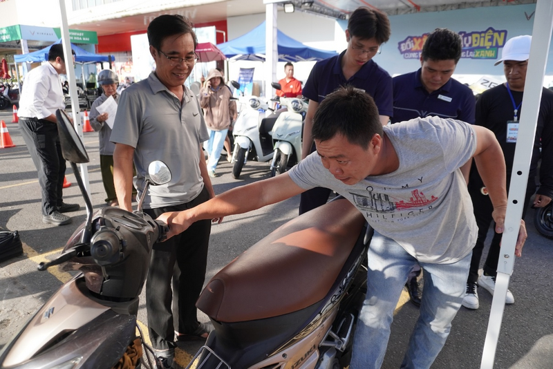 Ông Thông (bìa trái) mang xe máy xăng cũ đến định giá để đổi lấy VinFast Evo Grand Lite