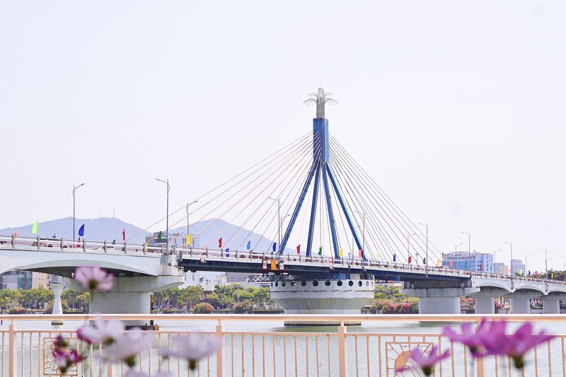 Ảnh 2: Những lá cờ được cắm trang trí chạy dọc cầu sông Hàn, nối dài thành dải màu rực rỡ, vừa tô điểm cảnh quan vừa lan tỏa tinh thần hướng về ngày đại lễ. Ảnh: Diễm Phúc