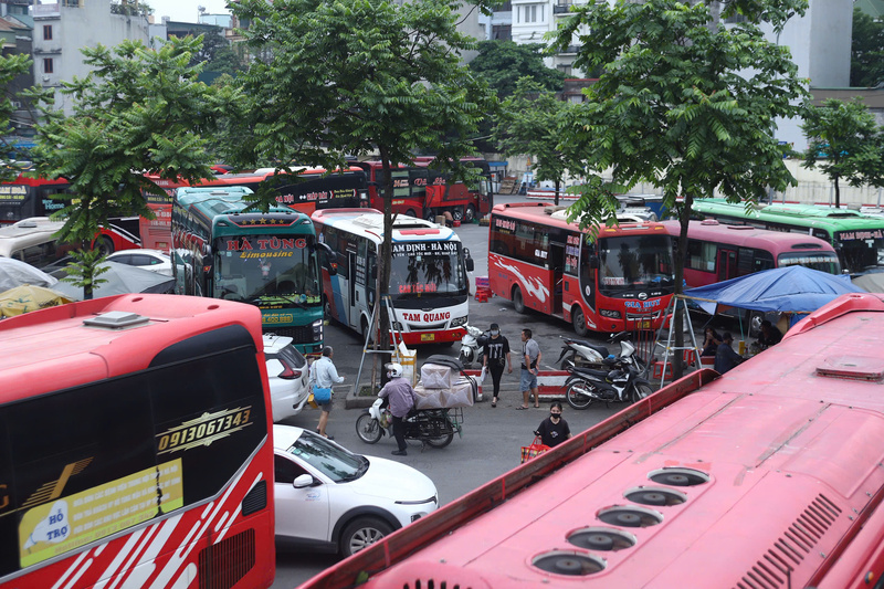 Ngoài sân, các xe đến giờ xuất bến vẫn chưa đủ khách, tài xế đứng ngóng, liên tục gọi điện tìm khách quen. Ảnh: Thái Mạnh