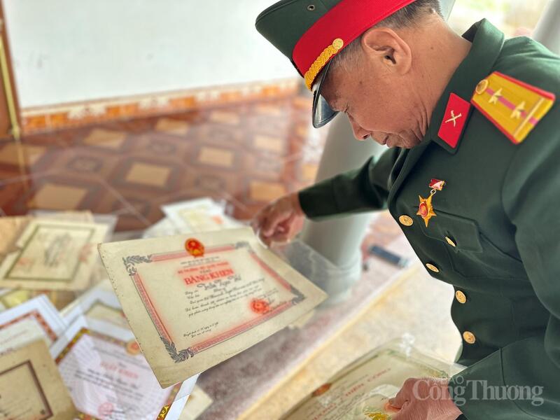 Người cựu chiến binh lặng lẽ ngắm nhìn những tấm bằng khen, giấy chứng nhận của mình. Ảnh: Minh Trang