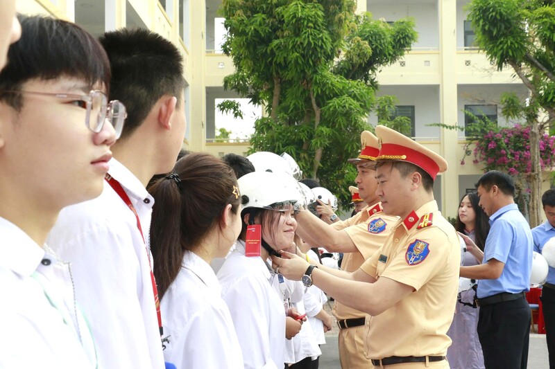 Cán bộ Đội CSGT đường bộ cao tốc số 4 hướng dẫn học sinh cách đội mũ bảo hiểm đạt chuẩn. Ảnh: Mai Liễu