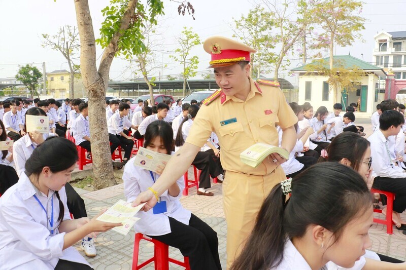 Cán bộ đơn vị phát tờ rơi hướng dẫn kỹ năng tham gia giao thông an toàn cho học sinh. Ảnh: Mai Liễu