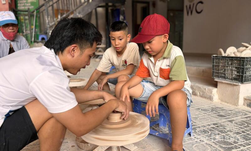 Nhiều gia đình dẫn các em nhỏ tham gia quá trình làm một chiếc cốc gốm tại Lò Bầu cổ Bát Tràng. Ảnh: Nhật Chi
