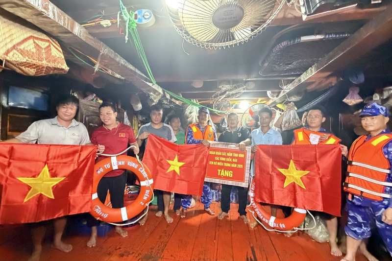 Đoàn khảo sát tặng quà, áo phao và cờ Tổ quốc cho các ngư dân đang đánh bắt trên biển. Ảnh: Diễm Phúc
