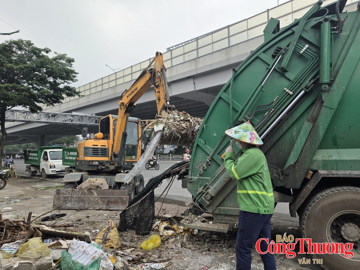 Máy xúc đưa rác, phế thải lên xe chuyên dụng để vận chuyển khỏi khu vực.