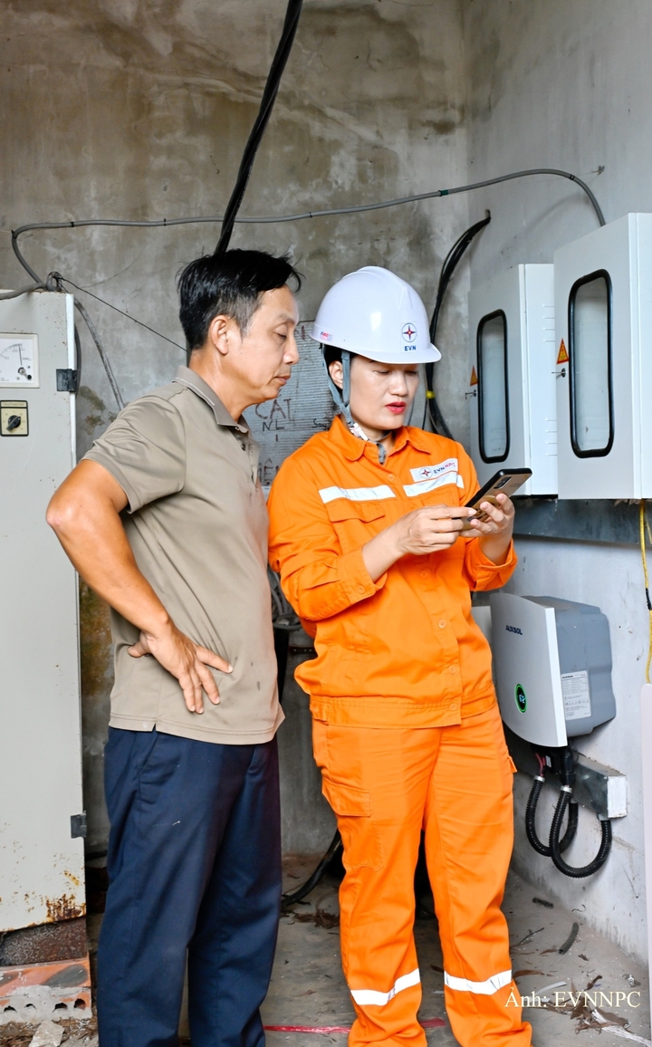 Nhân viên Điện lực Cẩm Xuyên, Công ty Điện lực Hà Tĩnh hướng dẫn khách hàng theo dõi hệ thống điện mặt trời mái nhà qua app trên điện thoại thông minh.