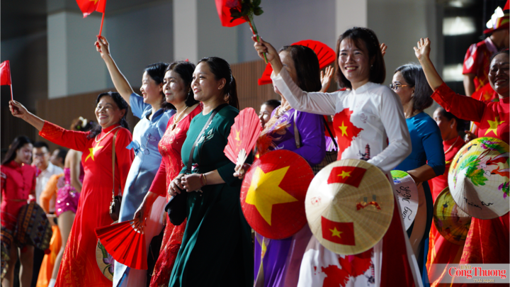 Phụ nữ Thủ đô tươi tắn trong tà áo dài, tay cầm nón lá và cờ đỏ sao vàng lan tỏa tinh thần mến khách.