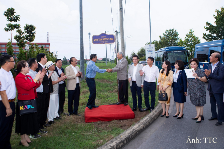 Ông Trần Duy Hy - Nhà sáng lập, Chủ tịch HĐQT Công ty CP Nhựa tái chế Duy Tân (áo vest kẻ, đứng giữa) bên con đường Duy Tân Recycling.