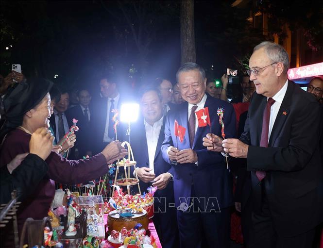 Tổng thống Thụy Sĩ Guy Parmelin bày tỏ sự thích thú với sản phẩm tò he của những nghệ nhân làng Xuân La - nét văn hóa dân gian Việt Nam độc đáo trên phố đi bộ hồ Hoàn Kiếm. Ảnh: Thống Nhất - TTXVN