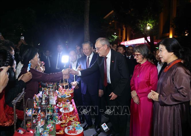 Tổng thống Thụy Sĩ Guy Parmelin và Phu nhân bày tỏ sự thích thú với sản phẩm tò he truyền thống do các nghệ nhân làng nghề Xuân La sáng tạo nên. Ảnh: Thống Nhất - TTXVN