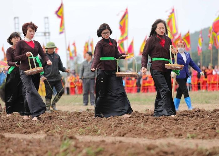 Các thôn nữ đi sau gieo hạt giống để cầu mong một năm mới với mùa màng tươi tốt bội thu. (Ảnh: Thanh Tùng/TTXVN)