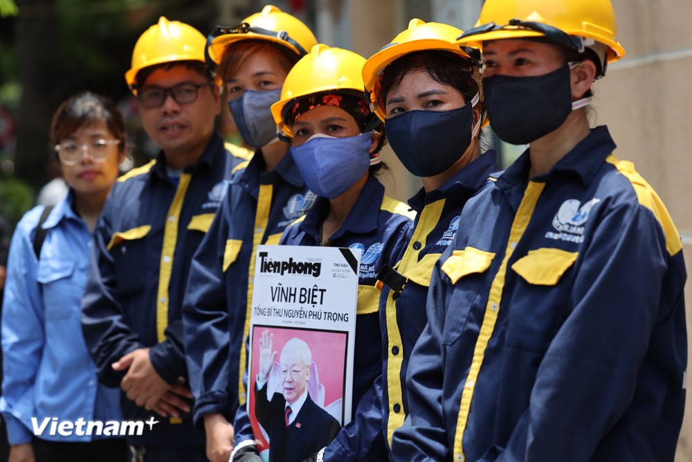Những người công nhân bất chấp nắng nóng, mang theo hình ảnh Tổng Bí thư xếp hàng ở khu vực nhà tang lễ. (Ảnh: Minh Sơn/Vietnam+) vnp_truydieu10.jpg