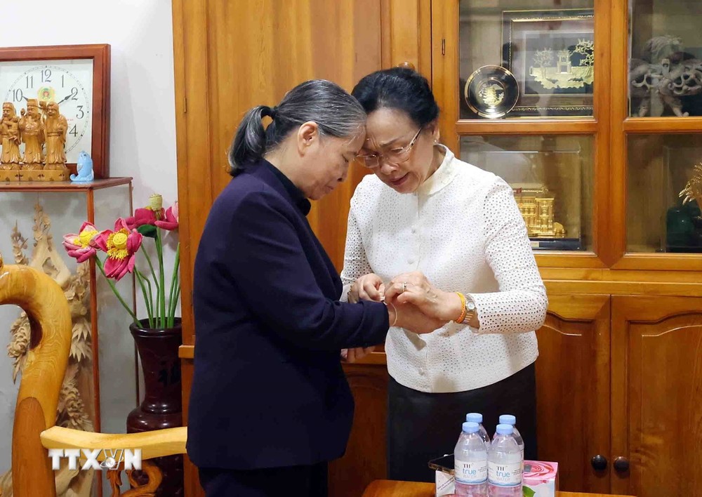 Bà Naly Sisoulith, Phu nhân Tổng Bí thư, Chủ tịch nước Lào Thongloun Sisoulith buộc chỉ cổ tay chúc may mắn, bình an tới bà Ngô Thị Mận, Phu nhân cố Tổng Bí thư Nguyễn Phú Trọng. (Ảnh: Phạm Kiên/TTXVN) ttxvn_phu nhan tong bi thu lao 2.jpg