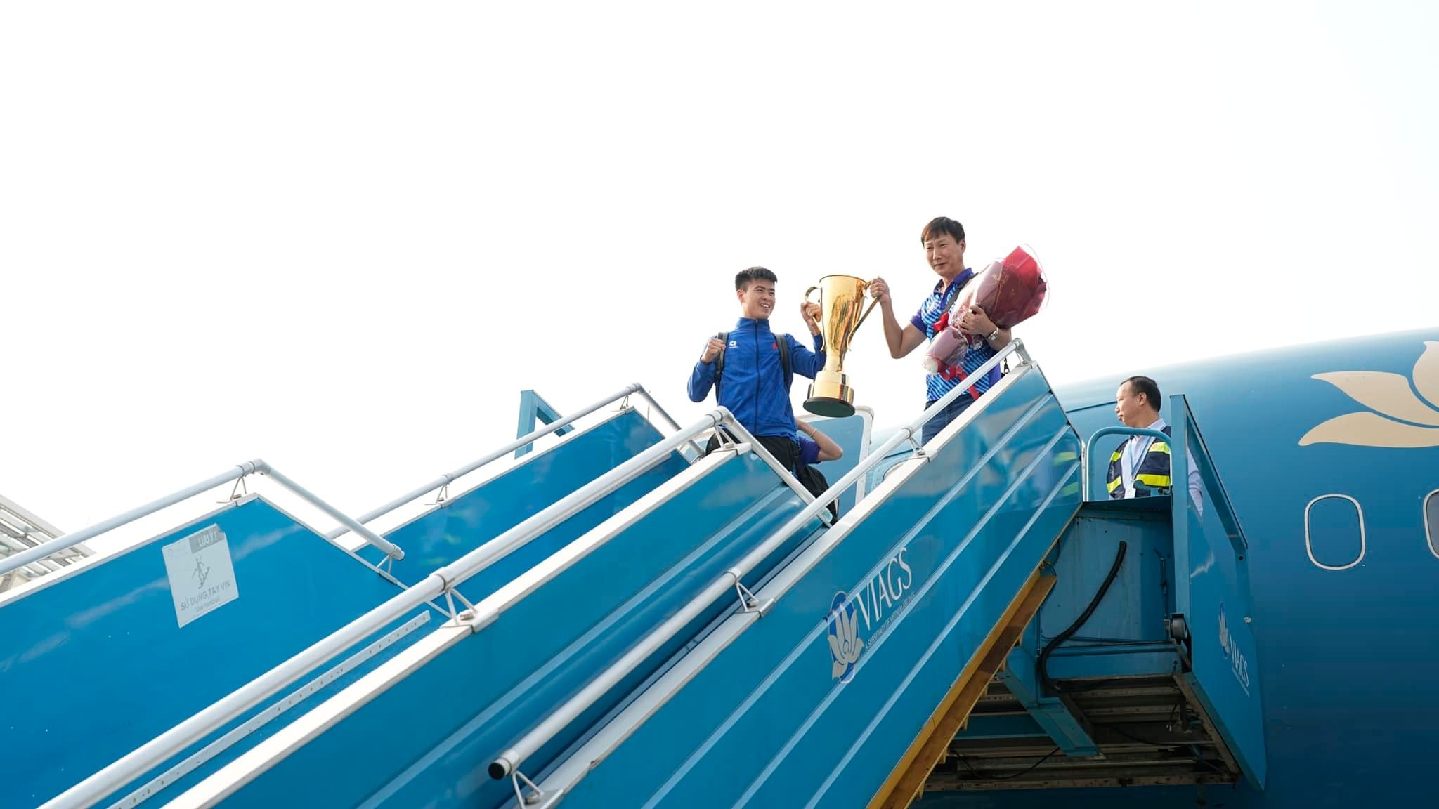 HLV trưởng Đội tuyển Việt Nam Kim Sang Sik và Đội trưởng Duy Mạnh nâng cao chiếc danh hiệu vô địch AFF Cup khi xuất hiện trước người hâm mộ. Ảnh: NIA