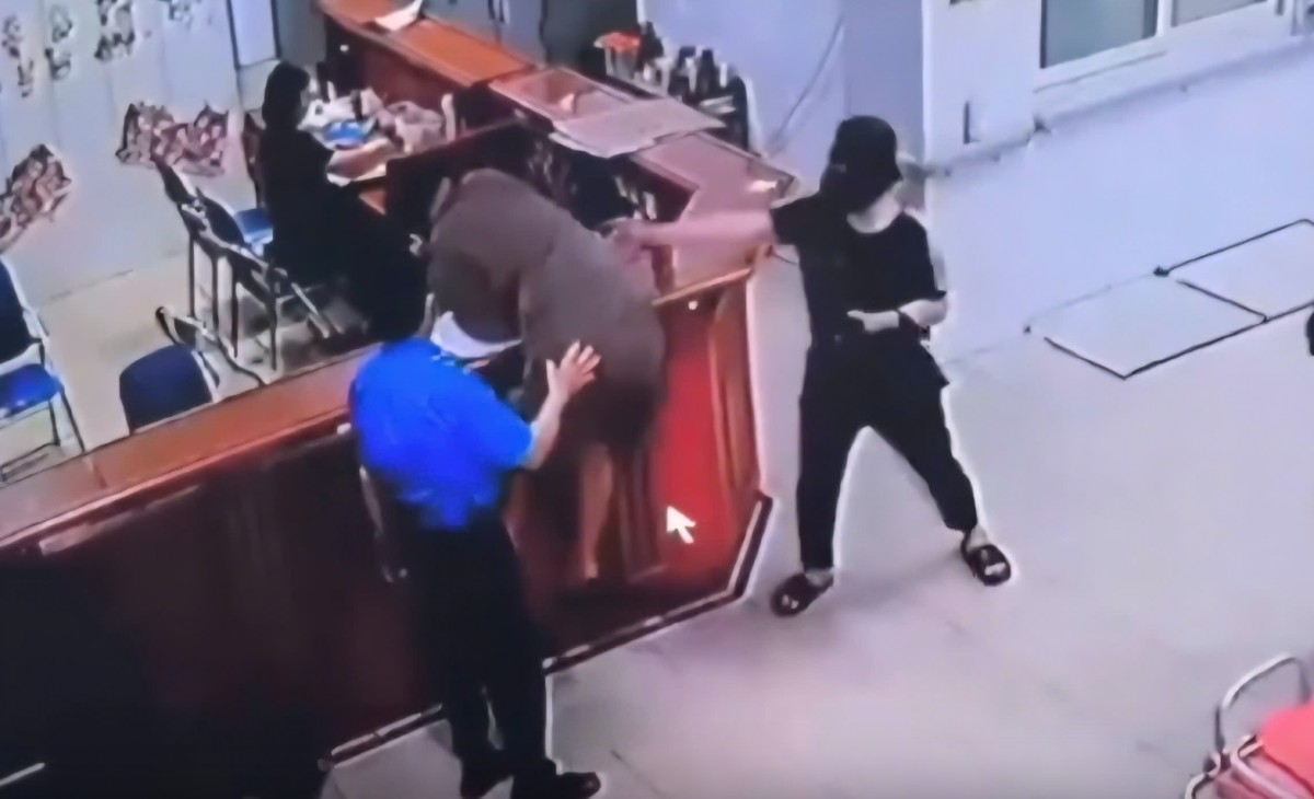 Hình ảnh người đàn ông chồm qua quầy làm thủ tục để hành hùng nhân viên y tế. Ảnh cắt từ clip.