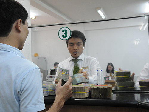 Theo NFSC, tổng tài sản của hệ thống ngân hàng năm 2013 đã tăng 15%. Trong ảnh: Khách hàng giao dịch tại một ngân hàng ở TP HCM