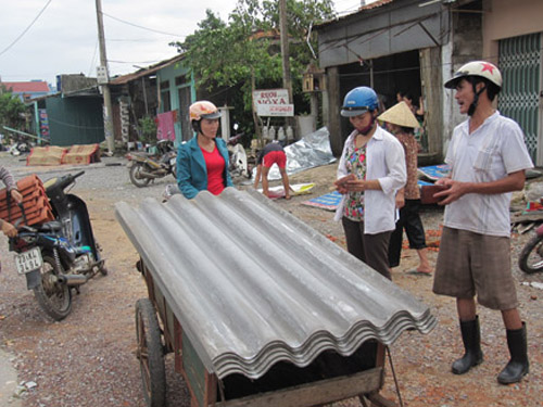 Bà con vận chuyển tấm lợp để sửa lại nhà sau mưa bão