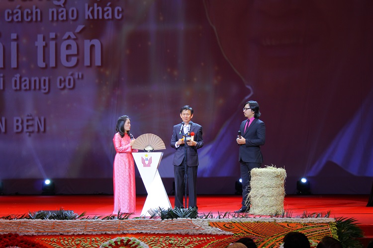 Ông Phan Tấn Bện bên cuộn rơm từ máy cuốn rơm của mình tại buổi lễ vinh danh cá nhân xuất sắc trong Đại hội Thi đua yêu nước toàn quốc lần IX