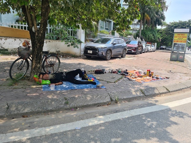 Cụ ông bán hàng tranh thủ nghỉ trưa trên đường Tôn Thất Thuyết