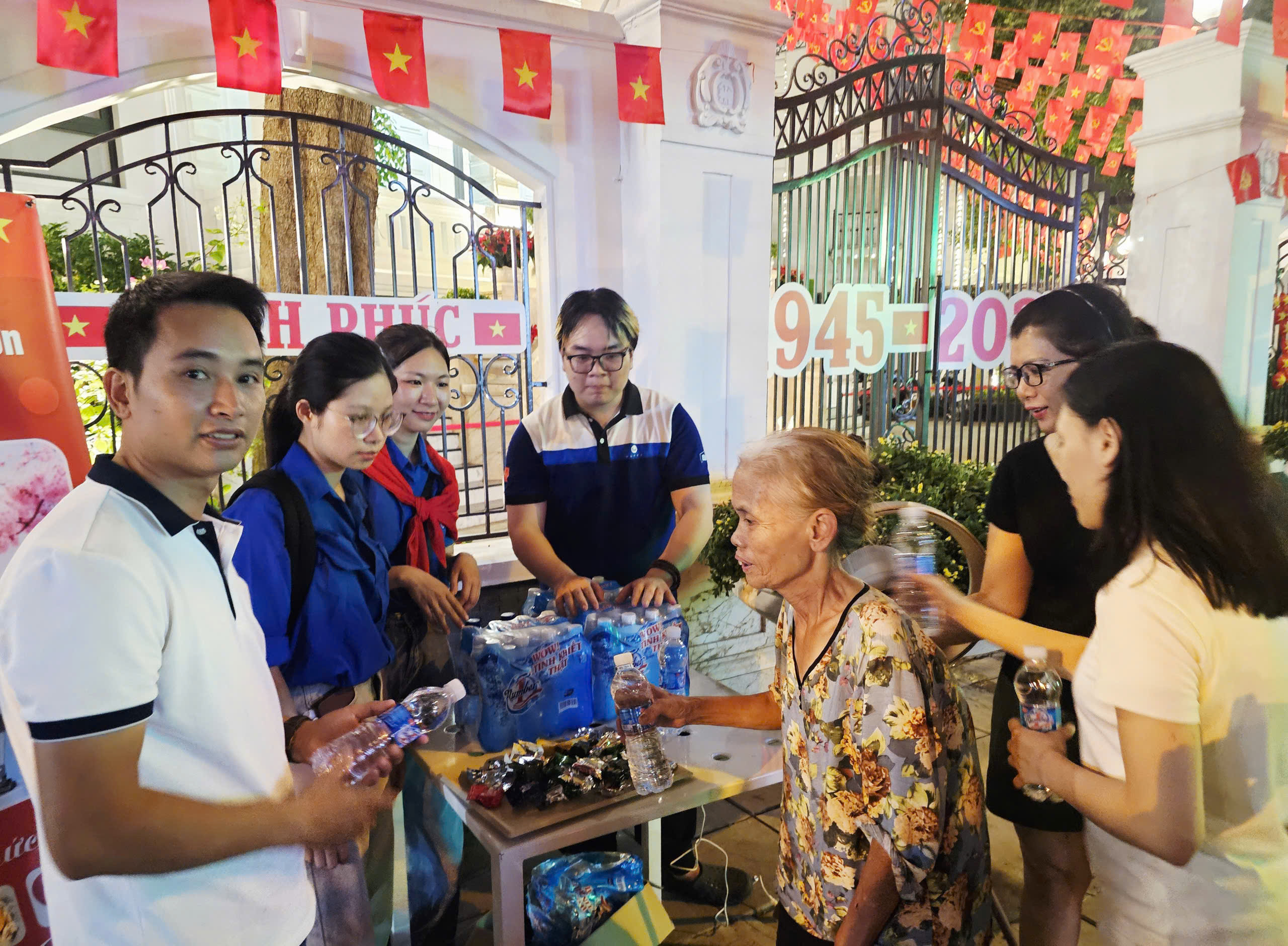 Cán bộ viên chức Trung tâm Truyền thông, Dữ liệu và Công nghệ số TP Hà Nội phối hợp cùng lực lượng đoàn thanh niên tặng nước uống miễn phí cho người dân đi xem hợp luyện diễu binh, diễu hành A80 tối 21/8