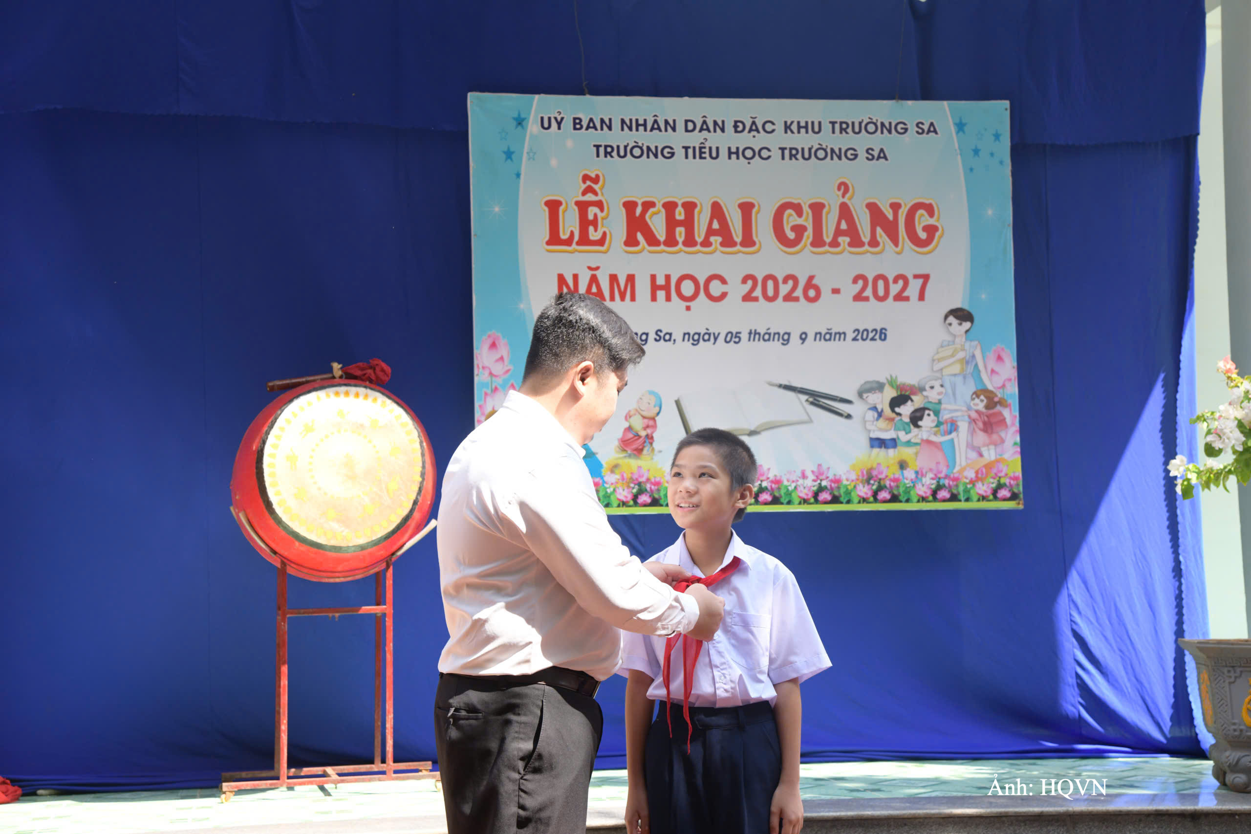 Thầy giáo Lê Xuân Hạnh trao khăn quàng đỏ cho học sinh Vi Quý Đăng ngày đầu năm học mới.